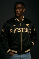 Stylish man wearing luxury black designer bomber jacket with gold star embellishments and metallic STARSTRUCK branding, featuring premium StarFlex fabric construction and celestial streetwear design
